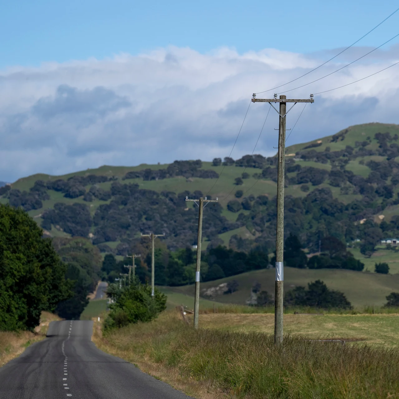 A rural distribution line running beside a country road into hill country.