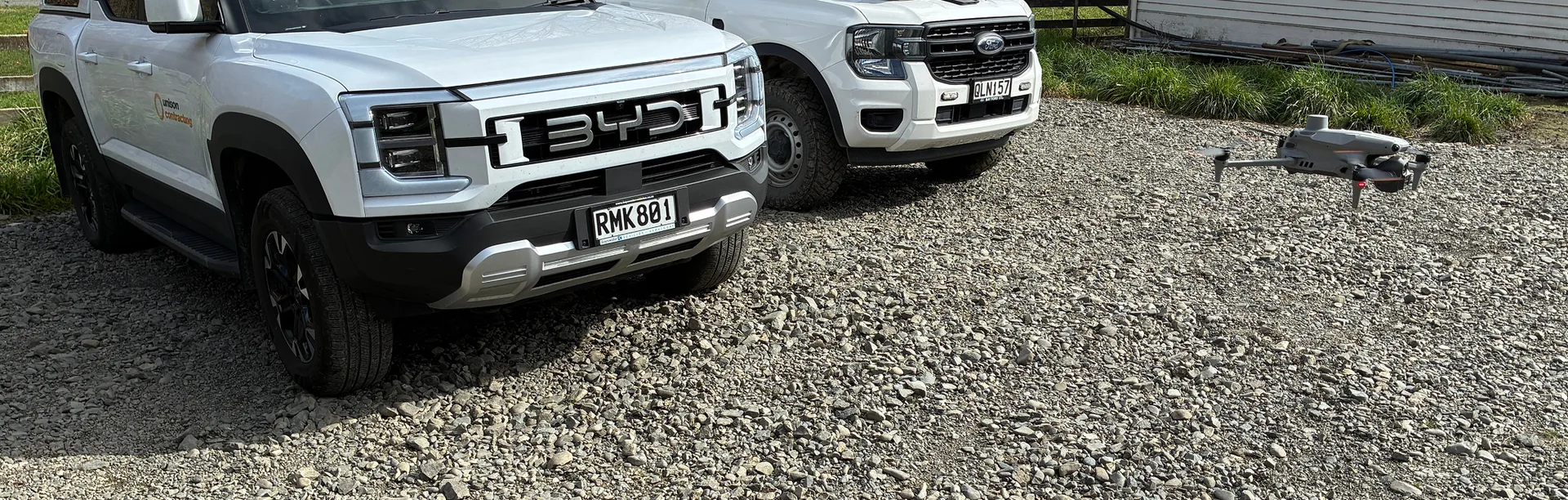 Two field vehicles parked on a rural gravel road with an inspection drone ready for take-off.